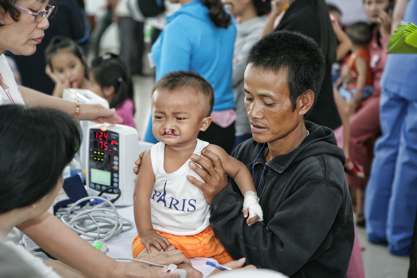 A father holds his young son with a cleft lip at an Operation Restore Hope screening day